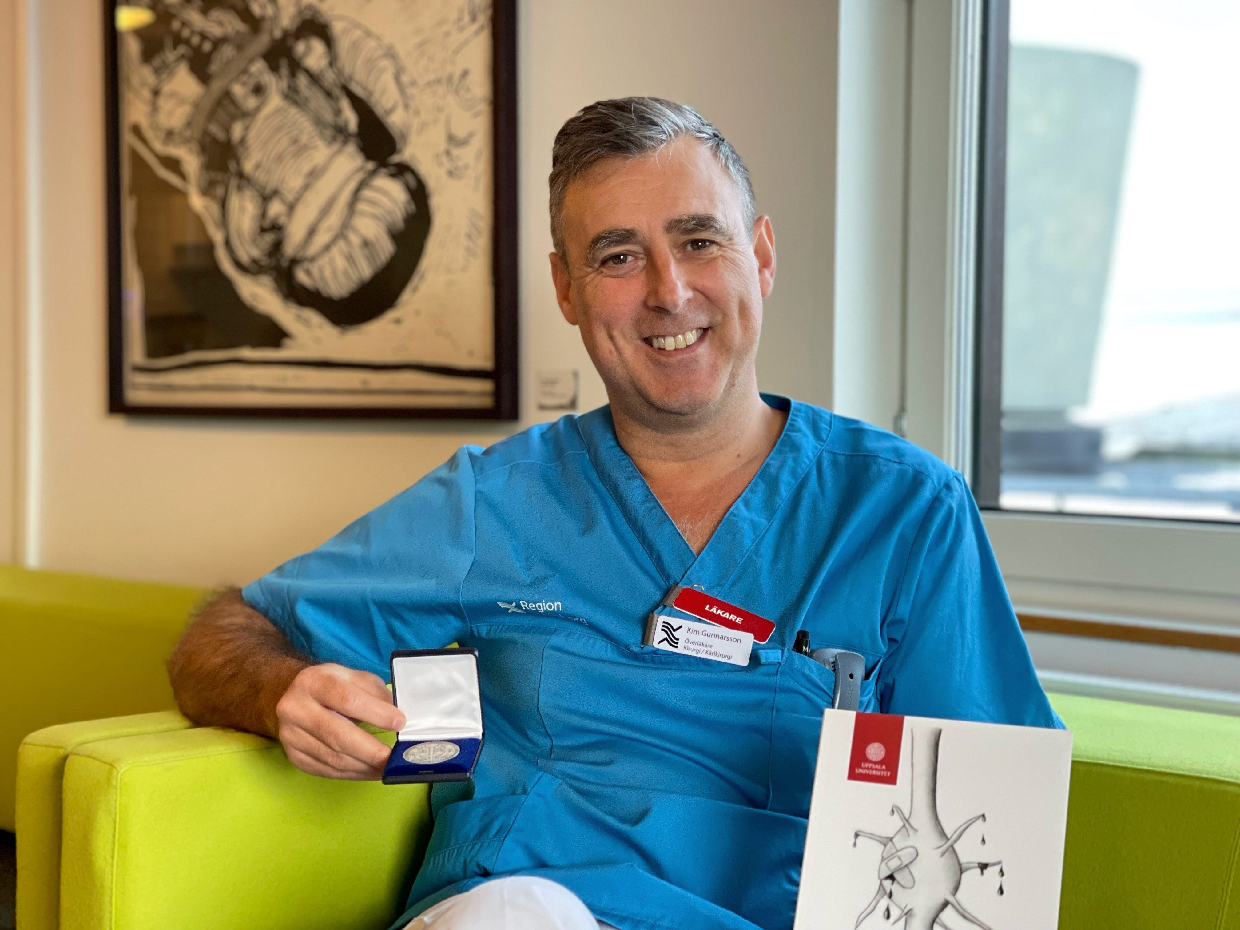 En man i operationskl&auml;der sitter p&aring; en gr&ouml;n soffa.